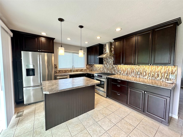 kitchen featuring dark brown cabinets, appliances with stainless steel finishes, a sink, wall chimney exhaust hood, and decorative backsplash