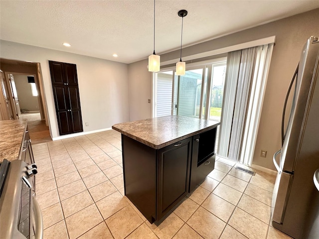 kitchen with freestanding refrigerator, stove, recessed lighting, a textured ceiling, and light tile patterned floors