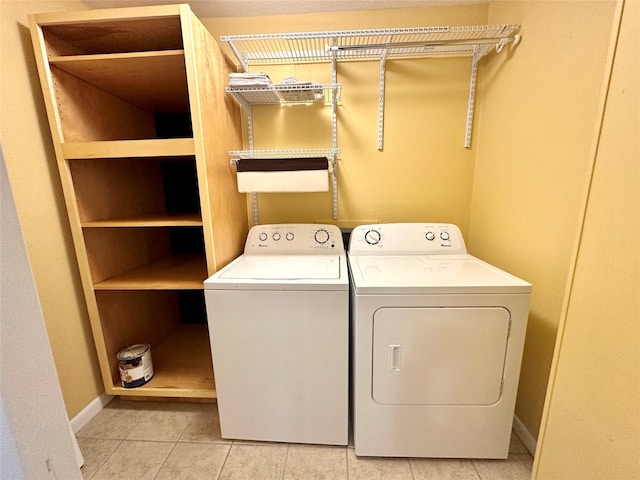 clothes washing area with baseboards, light tile patterned floors, laundry area, and washer and clothes dryer
