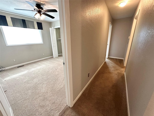 corridor featuring carpet flooring, baseboards, and visible vents