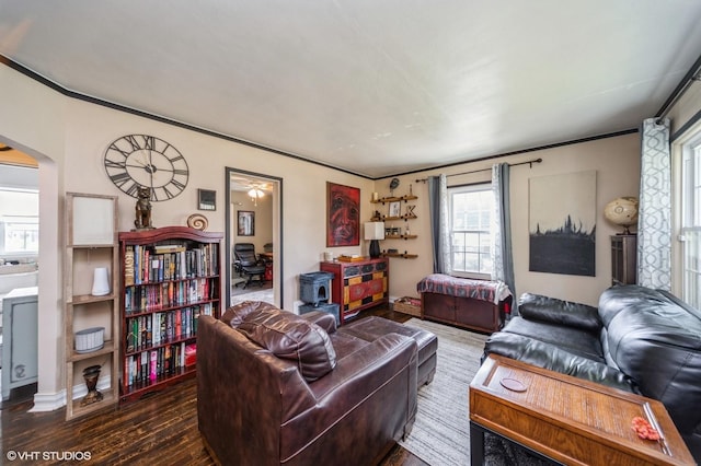 living area with dark wood-type flooring, arched walkways, and crown molding