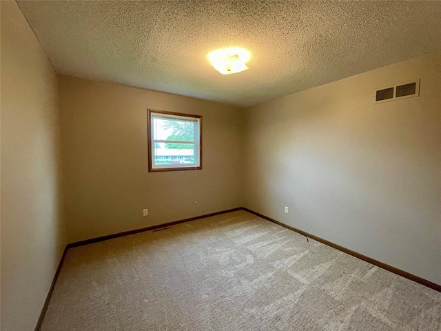unfurnished room with baseboards, light carpet, a textured ceiling, and visible vents