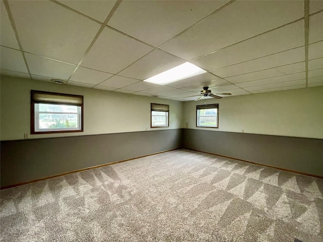 basement featuring carpet floors, baseboards, and a paneled ceiling