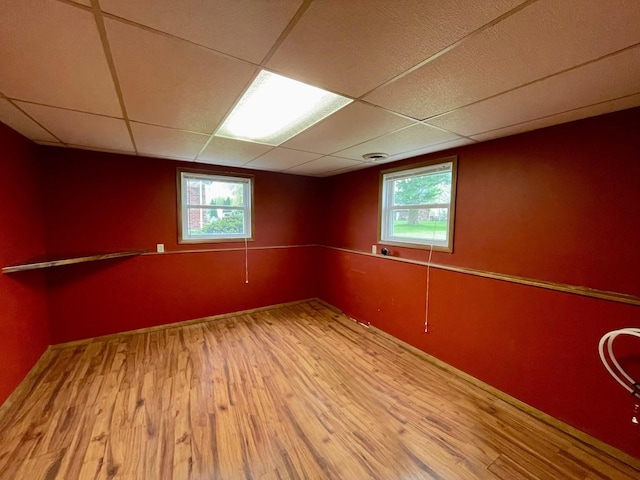 below grade area with plenty of natural light, wood finished floors, and a paneled ceiling