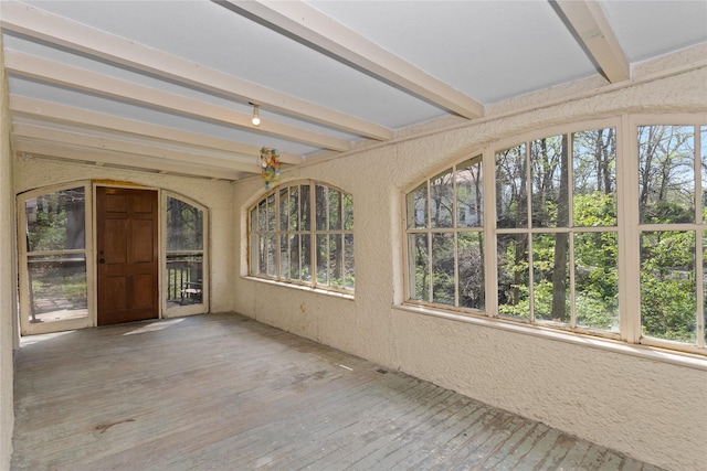 unfurnished sunroom with a textured wall, beam ceiling, and hardwood / wood-style flooring