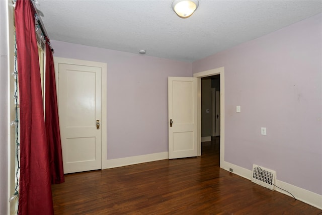 unfurnished room featuring a textured ceiling, baseboards, visible vents, and wood finished floors