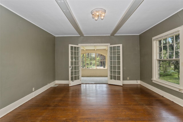 spare room featuring beamed ceiling, a healthy amount of sunlight, and wood finished floors