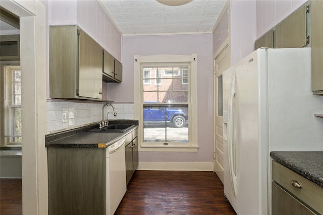 kitchen with white appliances, dark countertops, dark wood-style floors, and a sink