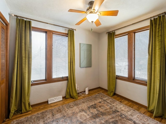 empty room with visible vents, baseboards, ceiling fan, and wood finished floors