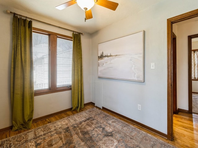 unfurnished room featuring a ceiling fan, baseboards, and wood finished floors