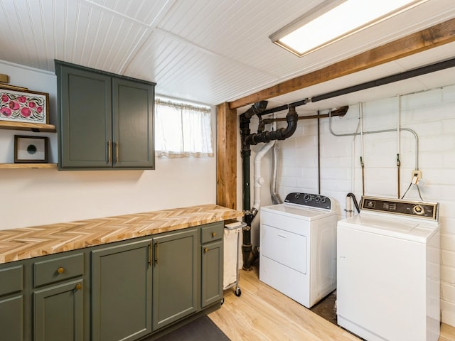 laundry room featuring washing machine and dryer, light wood finished floors, and cabinet space