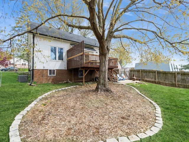 rear view of property featuring a lawn, a deck, stairs, and a fenced backyard