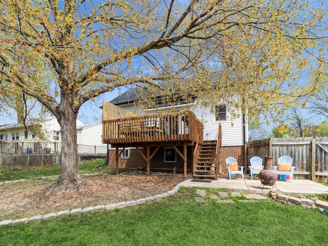 rear view of property with a deck, a patio area, stairway, brick siding, and a fenced backyard