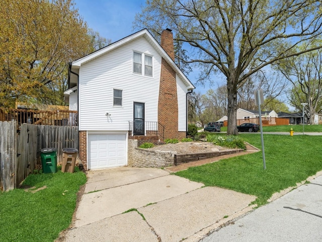 view of side of property featuring a chimney, a yard, brick siding, concrete driveway, and an attached garage