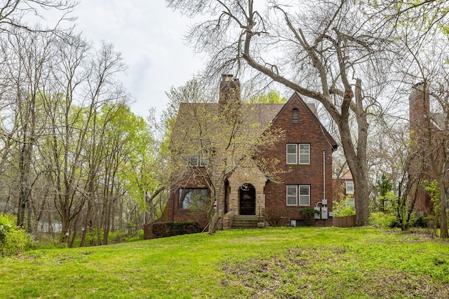 5502 Ingersoll Ave, Des Moines, IA 50312 - tudor home with a chimney, a front lawn, and brick siding