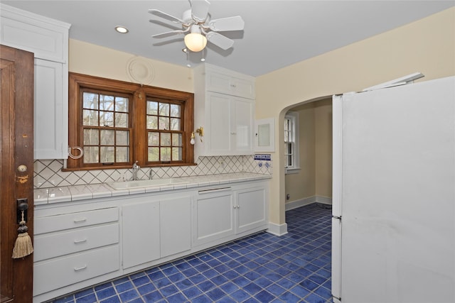 5502 Ingersoll Ave, Des Moines, IA 50312 - kitchen with freestanding refrigerator, white cabinetry, decorative backsplash, and a sink
