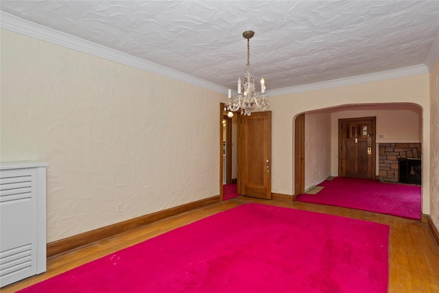 5502 Ingersoll Ave, Des Moines, IA 50312 - spare room featuring crown molding, wood finished floors, baseboards, arched walkways, and a notable chandelier
