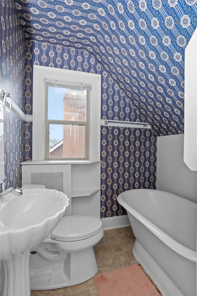 5502 Ingersoll Ave, Des Moines, IA 50312 - bathroom featuring lofted ceiling, toilet, baseboards, wallpapered walls, and a soaking tub