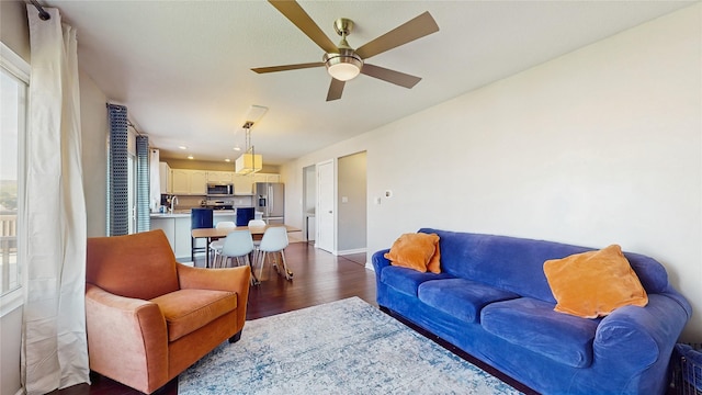 1009 SE 5th St, Grimes, IA 50111 - living area featuring dark wood finished floors, a ceiling fan, and baseboards