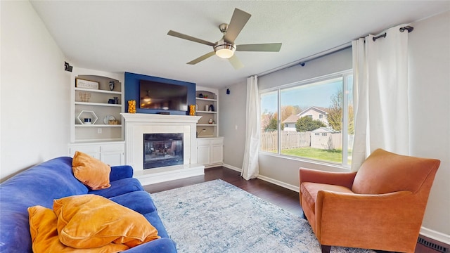 1009 SE 5th St, Grimes, IA 50111 - living area featuring ceiling fan, baseboards, a glass covered fireplace, and wood finished floors