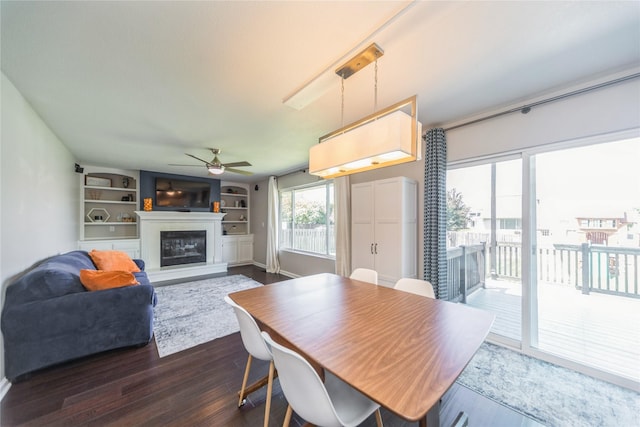 1009 SE 5th St, Grimes, IA 50111 - dining area featuring a ceiling fan, a glass covered fireplace, dark wood-style flooring, and built in shelves