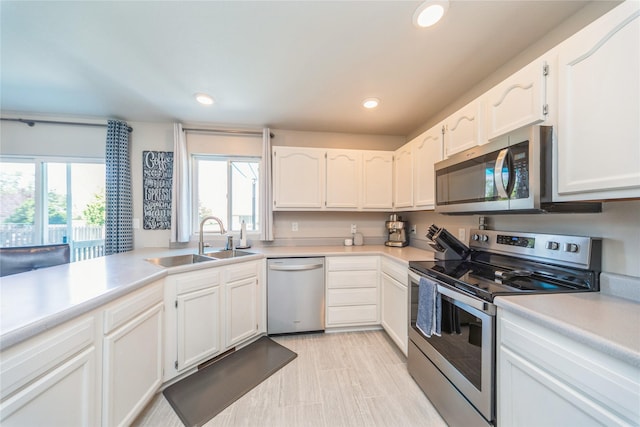 1009 SE 5th St, Grimes, IA 50111 - kitchen featuring stainless steel appliances, a sink, white cabinetry, light countertops, and recessed lighting