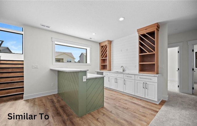 355 NW Red Oak Dr, Waukee, IA 50263 - kitchen featuring visible vents, a sink, light countertops, light wood-style floors, and white cabinetry
