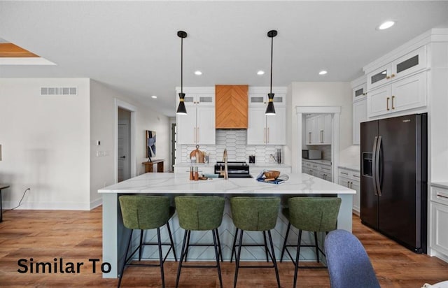 355 NW Red Oak Dr, Waukee, IA 50263 - kitchen featuring a kitchen bar, tasteful backsplash, a center island with sink, black appliances, and white cabinetry