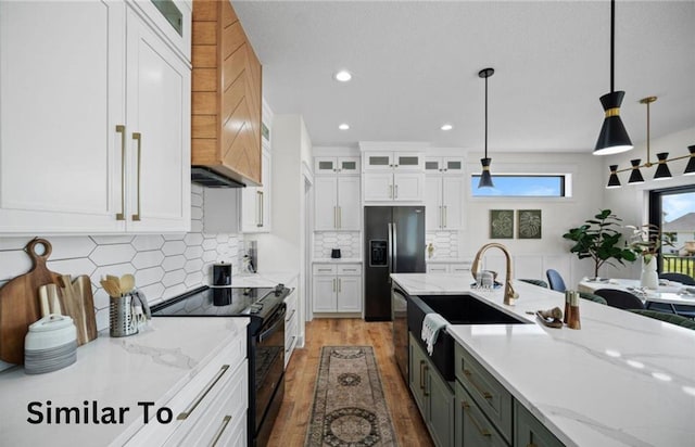 355 NW Red Oak Dr, Waukee, IA 50263 - kitchen with decorative light fixtures, wood finished floors, white cabinets, black appliances, and wall chimney exhaust hood