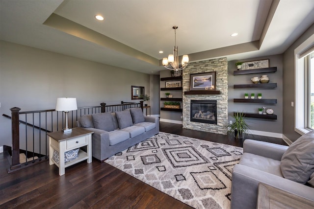 living room featuring an inviting chandelier, wood finished floors, baseboards, recessed lighting, and a raised ceiling