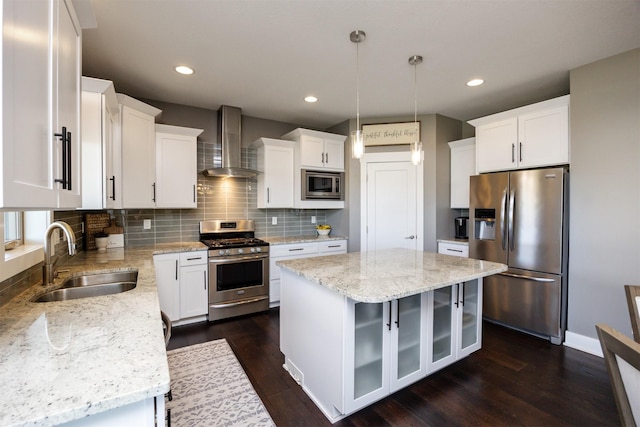 kitchen with decorative backsplash, glass insert cabinets, wall chimney range hood, a sink, and appliances with stainless steel finishes