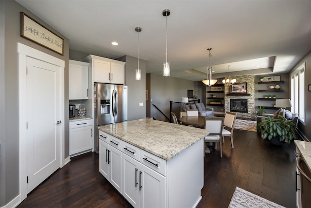 kitchen with stainless steel fridge, a fireplace, dark wood finished floors, and decorative light fixtures