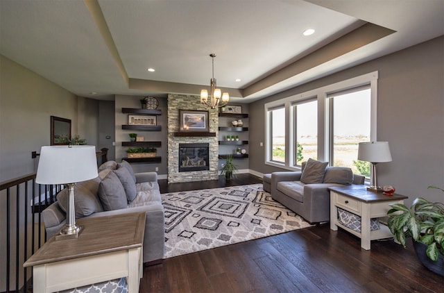 living room featuring an inviting chandelier, a tray ceiling, recessed lighting, and hardwood / wood-style floors