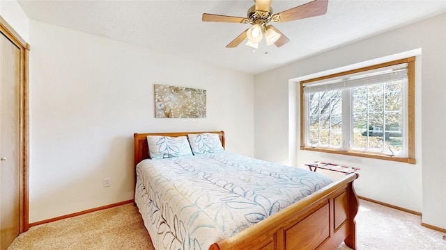 bedroom featuring a ceiling fan, baseboards, light carpet, and a closet