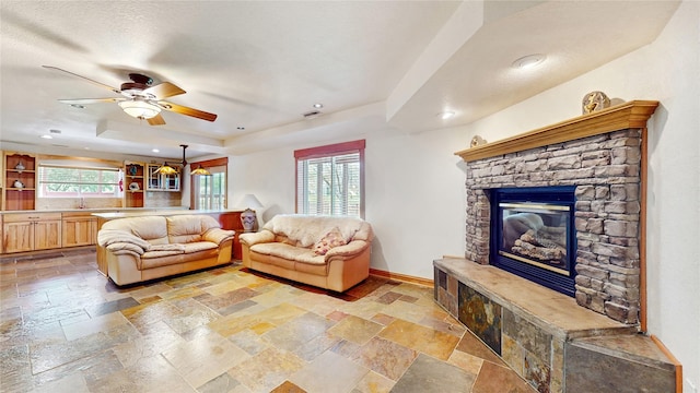 living room with a wealth of natural light, a tray ceiling, and stone tile floors
