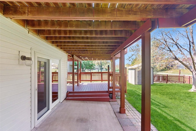 view of patio / terrace featuring an outdoor structure, a wooden deck, a fenced backyard, and a storage unit