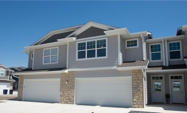 view of front of home featuring concrete driveway, stone siding, and a garage