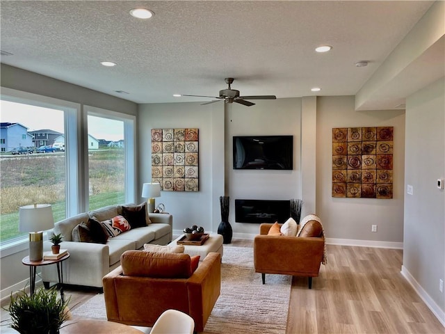living room with light wood-style floors, baseboards, recessed lighting, a textured ceiling, and a ceiling fan