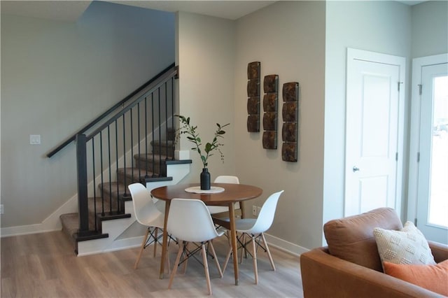 dining room with stairway, baseboards, and light wood-type flooring