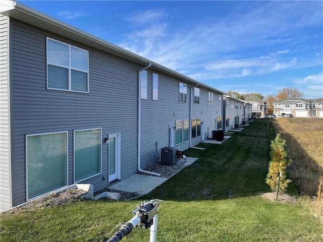 view of home's exterior with a lawn, central AC, and a residential view