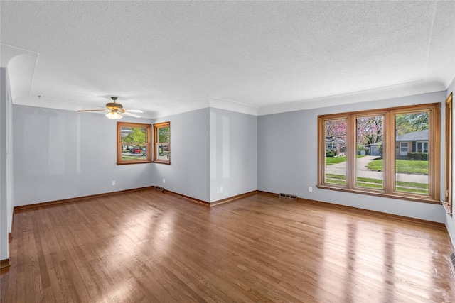 unfurnished room with a textured ceiling, a wealth of natural light, and wood finished floors
