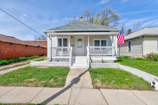 bungalow-style home featuring a porch, roof with shingles, a chimney, and a front yard