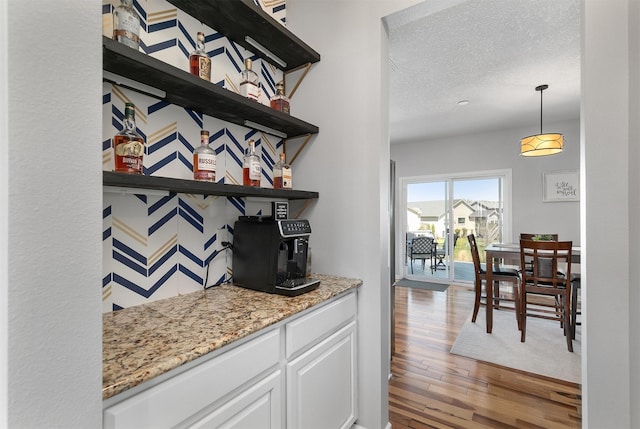 7517 NW 97th Ct, Johnston, IA 50131 - bar with wood finished floors, a textured ceiling, and pendant lighting
