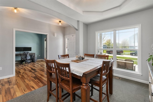 7517 NW 97th Ct, Johnston, IA 50131 - dining space featuring arched walkways, a raised ceiling, an office area, and wood finished floors