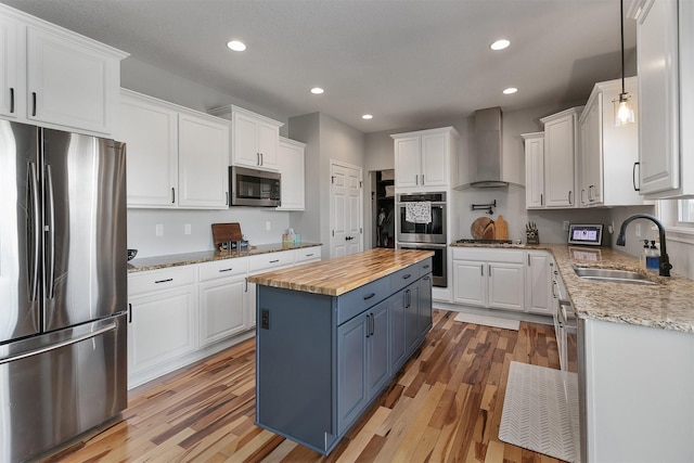7517 NW 97th Ct, Johnston, IA 50131 - kitchen with stainless steel appliances, wall chimney range hood, wooden counters, blue cabinets, and white cabinets