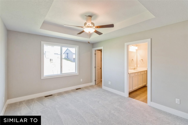 2912 6th Ave SW, Altoona, IA 50009 - unfurnished bedroom with visible vents, baseboards, a raised ceiling, ensuite bathroom, and light carpet