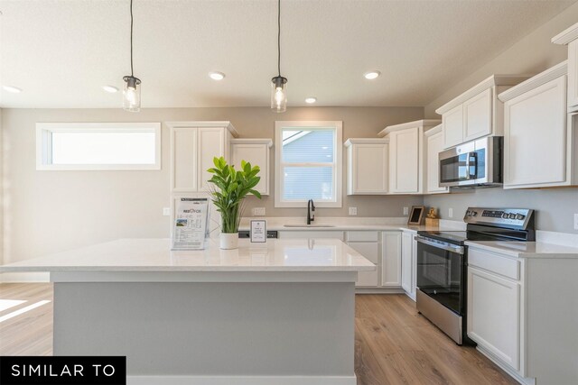 2917 6th Ave SW, Altoona, IA 50009 - kitchen with a center island, plenty of natural light, white cabinetry, a sink, and appliances with stainless steel finishes