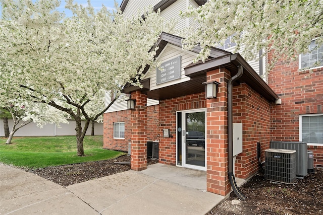 rear view of house with a patio, cooling unit, and brick siding