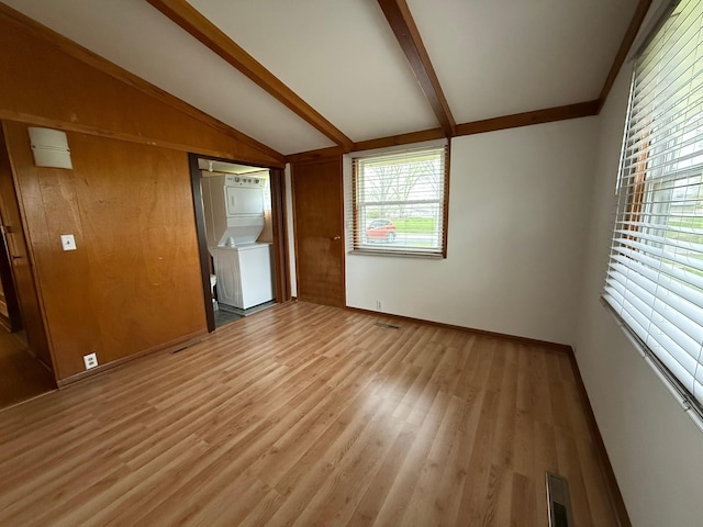 114 S Maple St, Gilman, IA 50106 - unfurnished room with visible vents, stacked washer / dryer, baseboards, light wood-type flooring, and lofted ceiling with beams