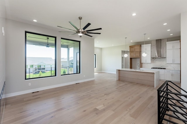 unfurnished living room featuring a sink, light wood finished floors, a ceiling fan, and recessed lighting